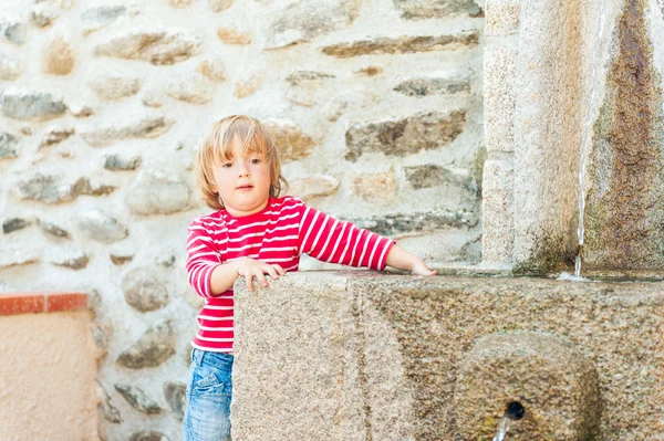 Bir çeşme ile güzel yaz gününde oynayan sevimli yürümeye başlayan çocuk — Stok fotoğraf