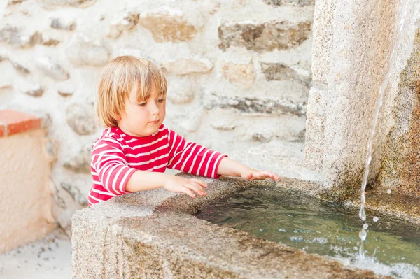 Cute toddler boy playing with a fountain on a nice summer day — Stock Photo, Image
