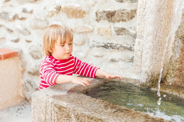 Menino bonito brincando com uma fonte em um belo dia de verão — Fotografia de Stock