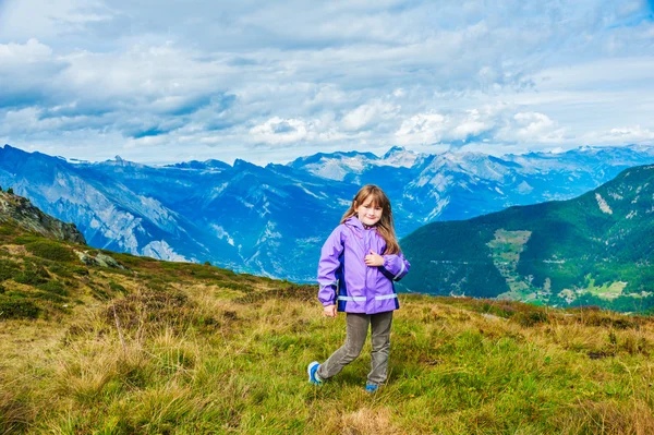 Nettes kleines Mädchen in den Bergen, in lila Regenjacke und Samthose — Stockfoto