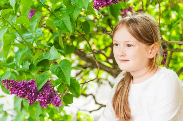 Portrait extérieur d'une jolie petite fille contre un beau lilas par une belle journée de printemps — Photo