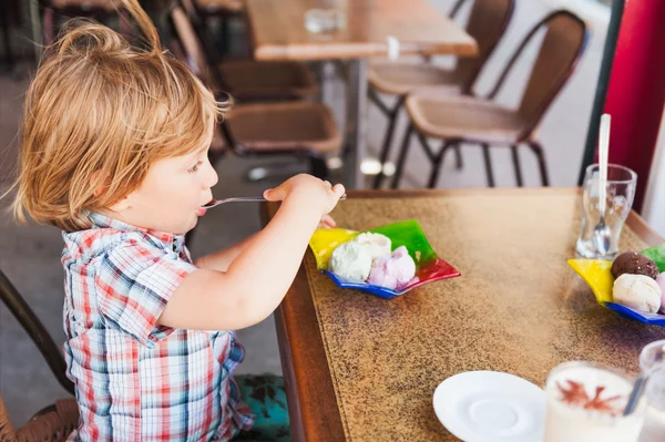 Menino bonito comendo sorvete em um café — Fotografia de Stock