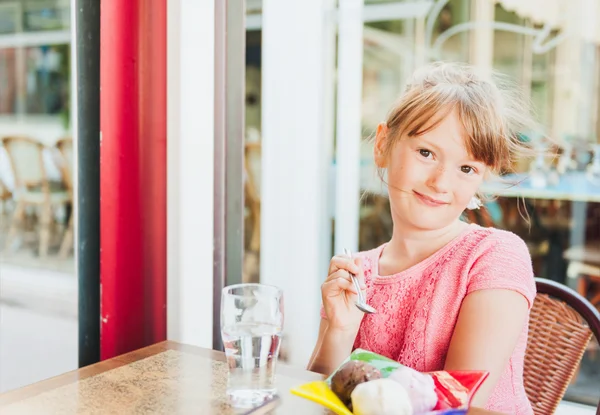 Cute little girl eating ice cream in a cafe — Stock Photo, Image