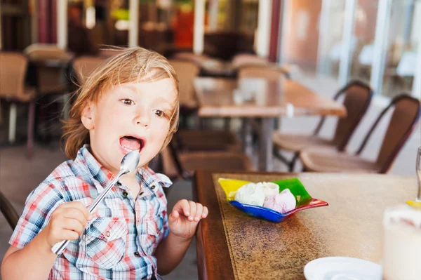 Søt småbarnsgutt som spiser iskrem på kafeen. – stockfoto