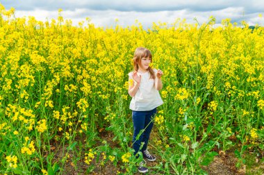 Açık bir kırsal çiçeklerle oynayan sevimli küçük kız portresi