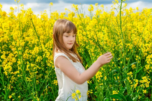 Potret luar ruangan seorang gadis kecil yang lucu bermain dengan bunga di pedesaan — Stok Foto