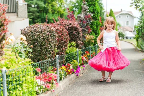 Menina bonita vestindo saia de tutu rosa brilhante e top branco, de pé ao lado de arbustos de hortênsia — Fotografia de Stock