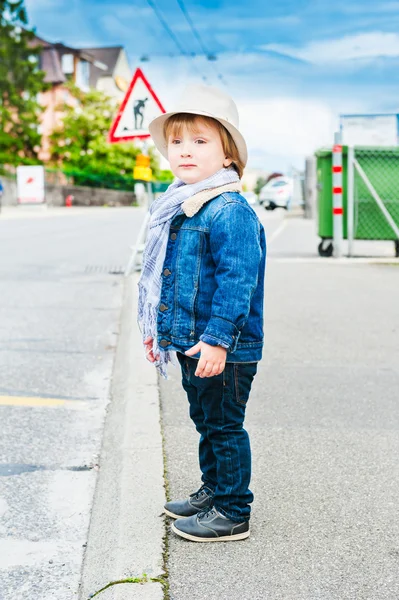 Outdoor portrait of a cute toddler boy, wearing hat, scarf, jeans jacket abd black jeans — Stock Photo, Image
