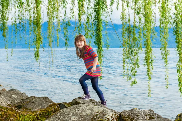 Outdoor portrait of a cute little girl on a nice sunny day, playing next to beautiful lake — Stock Photo, Image