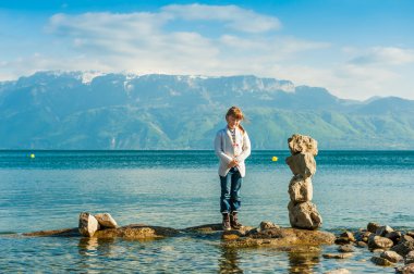 Sevimli küçük kız ve taş heykel karşı dağlar göl kenarında ile güzel manzara