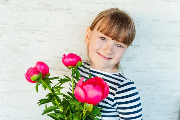 Ritratto di una graziosa bambina con peonie rosa — Foto Stock