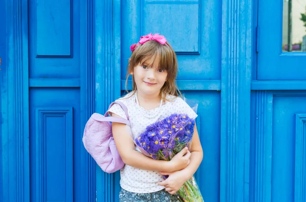 Adorable little girl with bouquet of violet flowers — Stock Photo, Image