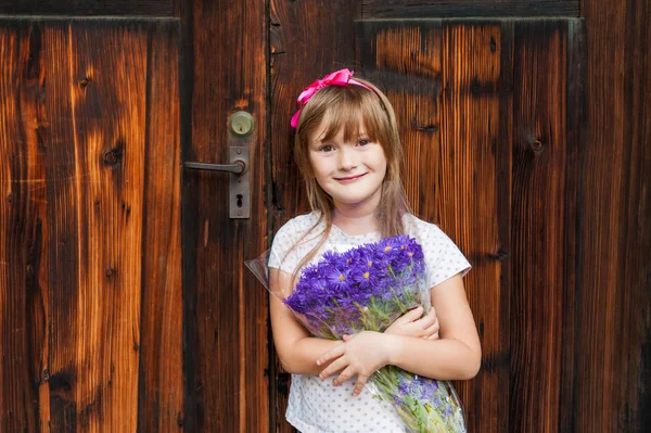 Adorabile bambina con mazzo di fiori viola — Foto Stock