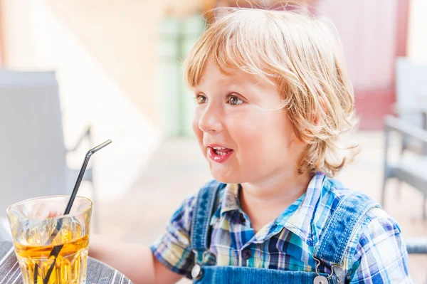 Menino adorável bebendo suco de maçã em um café — Fotografia de Stock