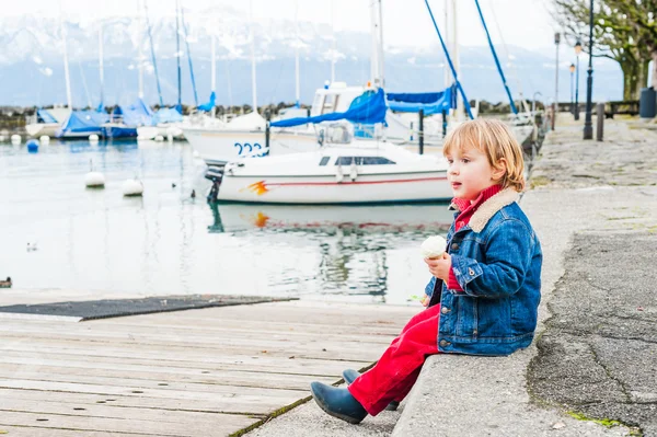 Adorable tout-petit garçon mangeant de la crème glacée dans un port un beau début de journée de printemps — Photo