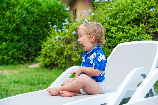 Cute toddler boy sitting on a lounge with funny expression on his face — Stock Photo, Image