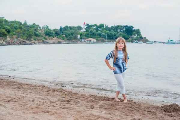 Schattig klein meisje dat op een zandstrand staat en een jurk en een witte jeans draagt — Stockfoto