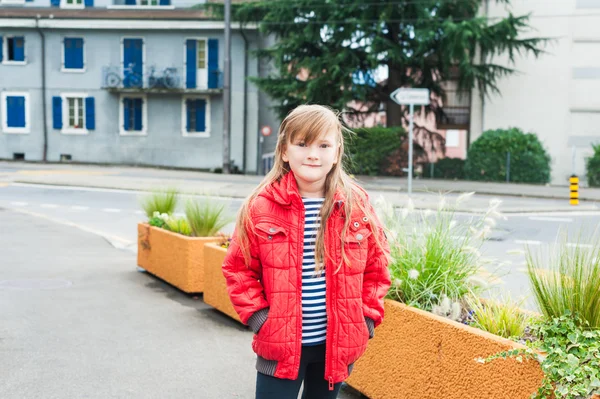 Venkovní portrét roztomilá holčička ve městě, na sobě teplé červené sako — Stock fotografie