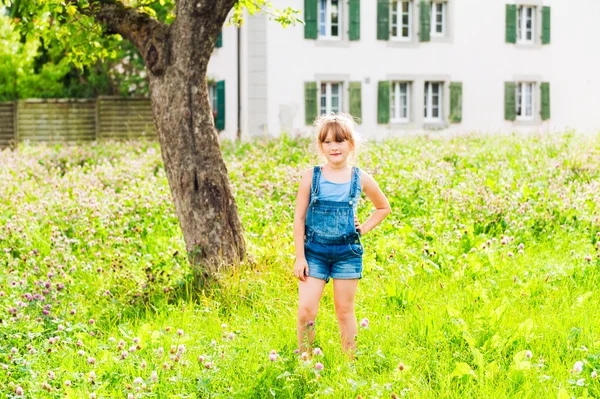Utomhus porträtt av en söt liten flicka i en trädgård på en fin sommardag — Stockfoto
