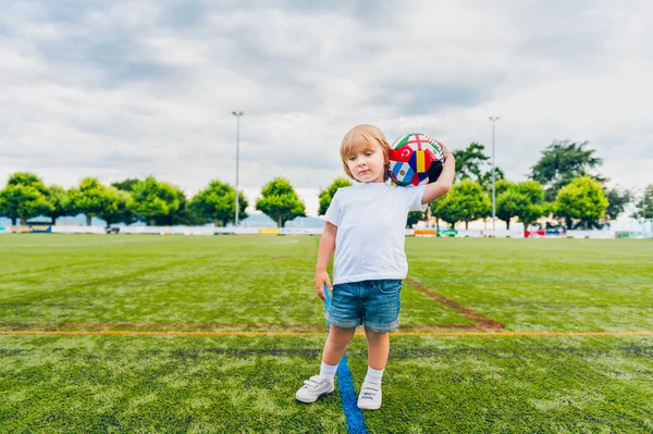 Draguta copil baiat joc cu o minge pe un stadion — Fotografie, imagine de stoc