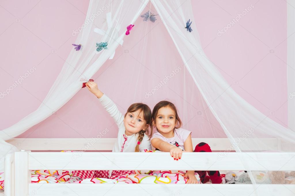 Adorable little girls playing together on the bed