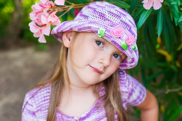 花を持つ美しいニット紫の帽子でかわいい女の子の肖像画間近します。 — ストック写真