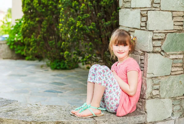 Außenporträt eines niedlichen kleinen Mädchens an einem schönen sonnigen Tag, das Korallenkleid und bedruckte Leggings trägt — Stockfoto