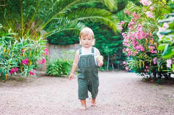 可爱的蹒跚学步的男孩行走在他手里的花 — 图库照片
