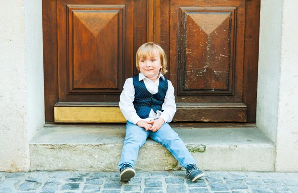 Zewnątrz portret toodler ładny chłopiec, siedząc na schodach w mieście, noszenie ubrania piękne święto — Zdjęcie stockowe