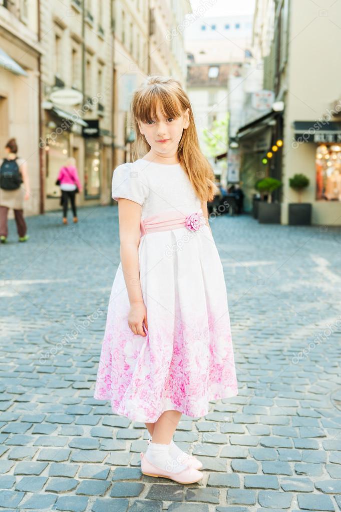 Outdoor portrait of a cute little girl in a beautiful dress in a city