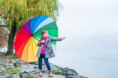 Büyük renkli şemsiye ile tatlı bir küçük kız portresi