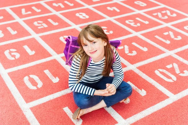 Close up portrait of a cute little girl with backpack in a schoolyard — Stock Photo, Image