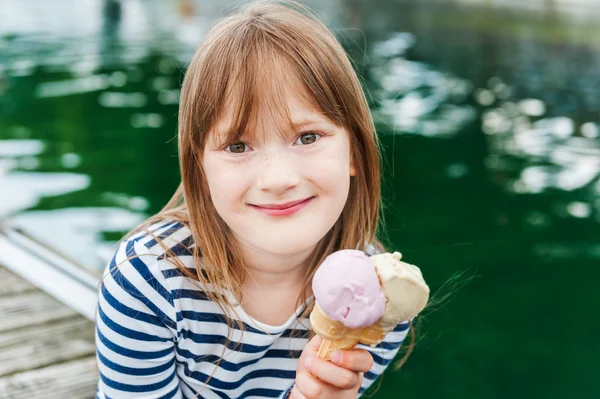 Открытый портрет милой маленькой девочки, поедающей мороженое в порту — стоковое фото