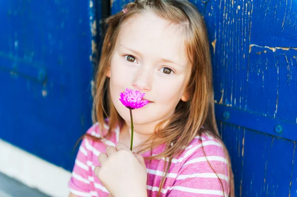 Outdoor close up portrait of a 7 years old girl with pink flower — Stock Photo, Image
