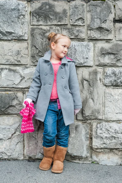 Ritratto all'aperto di una graziosa bambina in cappotto grigio, jeans e stivali marroni — Foto Stock