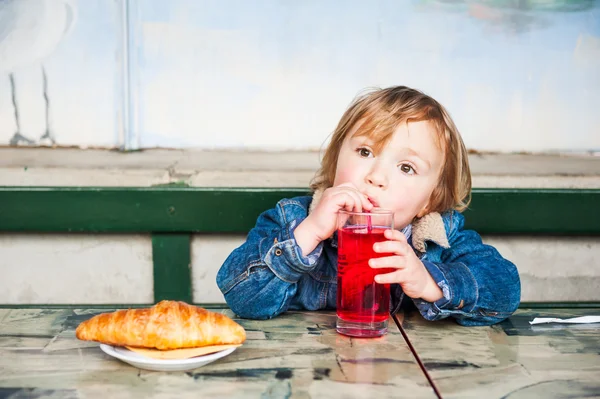 Cute toddler boy having a snack on a terrace in a cafe — Stock Photo, Image