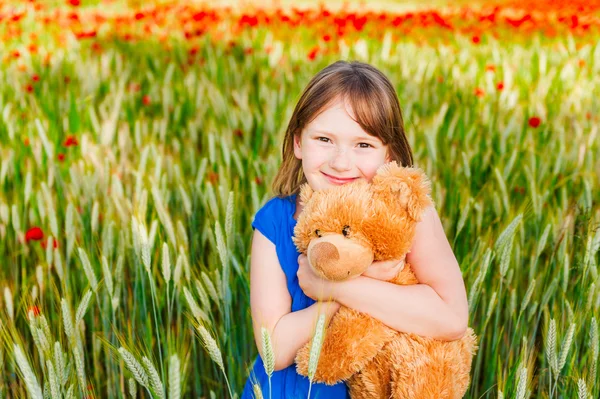 Ritratto estivo di una graziosa bambina che gioca con l'orsacchiotto in un campo di grano — Foto Stock