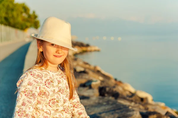 Göl kenarına yanında oturan sevimli küçük bir kız günbatımı porait — Stok fotoğraf