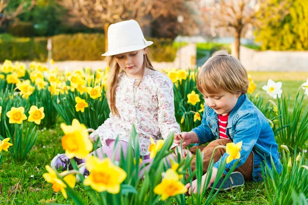 Rozkošné děti si hrají s květinami na pěkný slunný jarní den — Stock fotografie