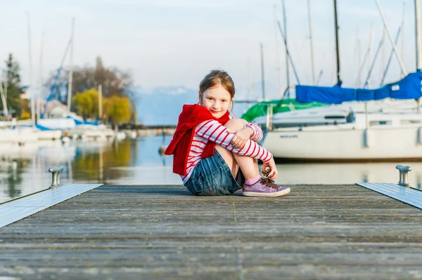 Niedliches kleines Mädchen, das an einem schönen sonnigen Tag auf einem Steg ruht — Stockfoto