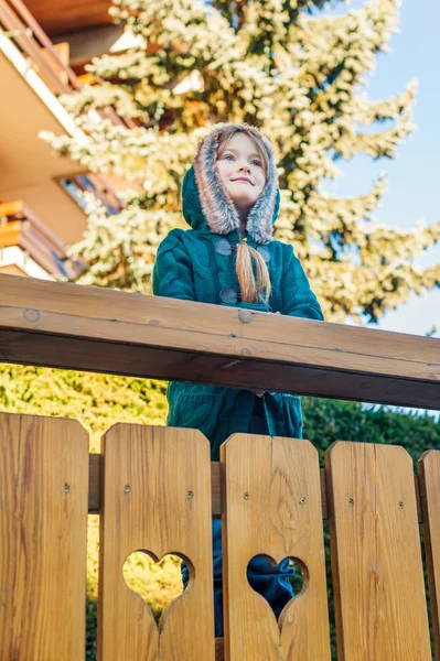 Portrait extérieur d'une jolie petite fille en vacances d'hiver, debout à côté d'une clôture de style alpin avec des cœurs — Photo