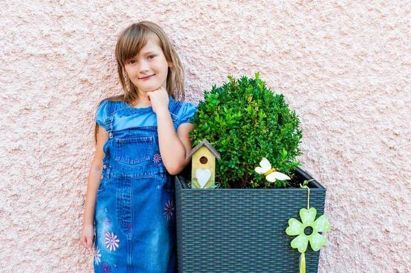 Menina bonito de pé ao lado da decoração do jardim — Fotografia de Stock