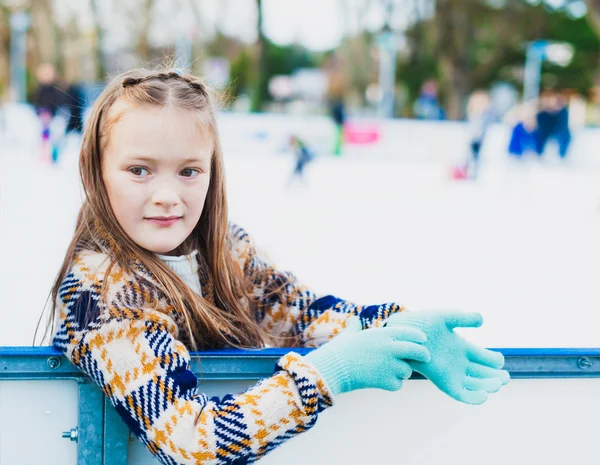 Söt liten flicka lära sig åka skridskor med stöd på en fin vinterdag — Stockfoto