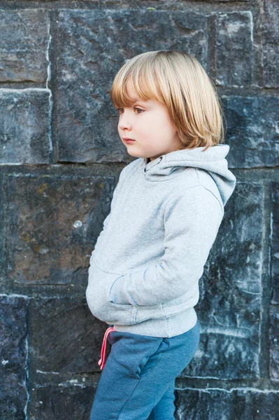 Outdoor portrait of a cute little boy against stone wall — Stock Photo, Image