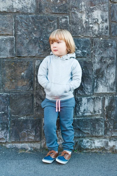 Outdoor portrait of a cute little boy against stone wall — Stock Photo, Image