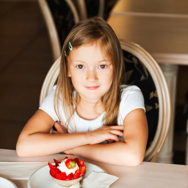 Cute little girl eating strawberry cake in a cafe — Stock Photo, Image