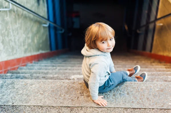 Adorable niño sentado en las escaleras de una ciudad — Foto de Stock