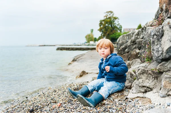 Lindo chico toodler divertirse al aire libre, jugando al lado del lago en un día lluvioso — Foto de Stock