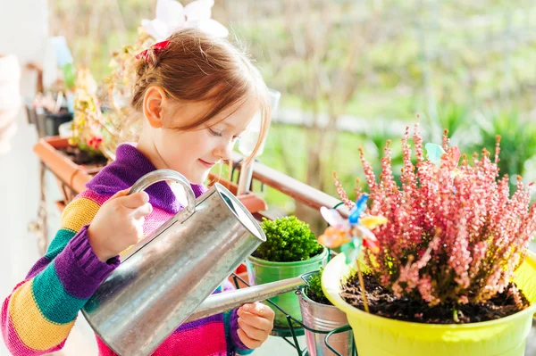 Adorable petite fille arrosant des plantes sur le balcon par une belle journée ensoleillée — Photo