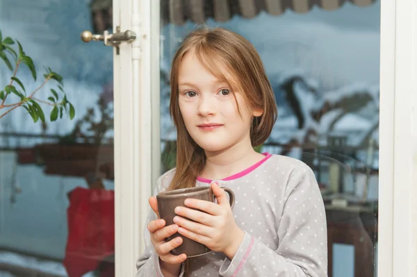 Adorável menina em pijama bebendo sua manhã chocolate quente pela janela — Fotografia de Stock